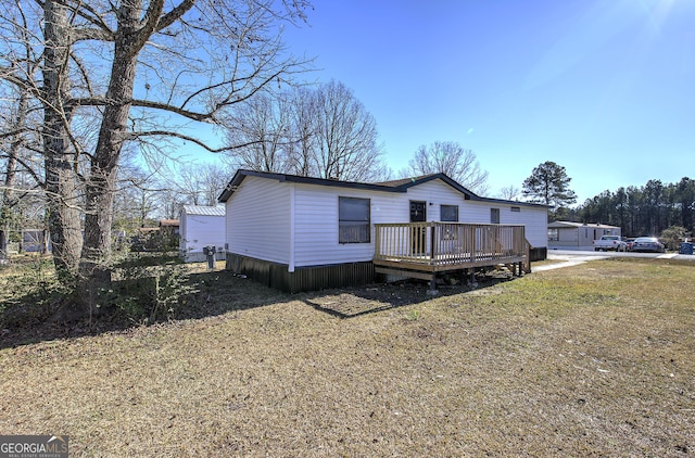 manufactured / mobile home featuring a front lawn and a wooden deck