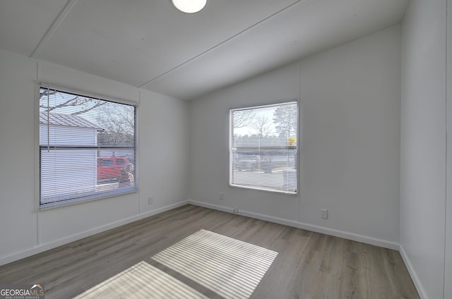 unfurnished room with vaulted ceiling and light wood-type flooring