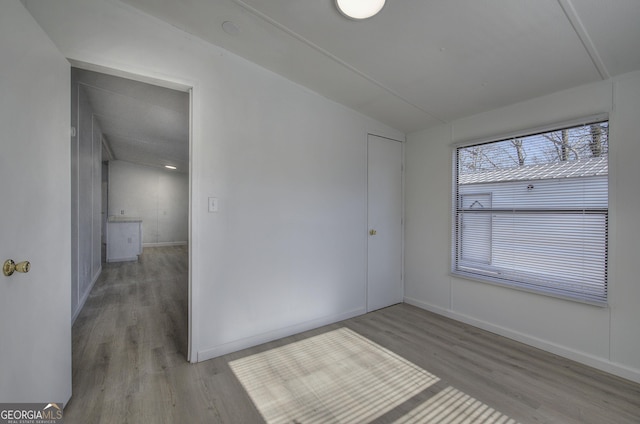 unfurnished room with light wood-type flooring and vaulted ceiling