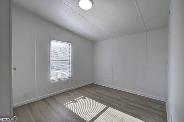 empty room with light wood-type flooring and vaulted ceiling