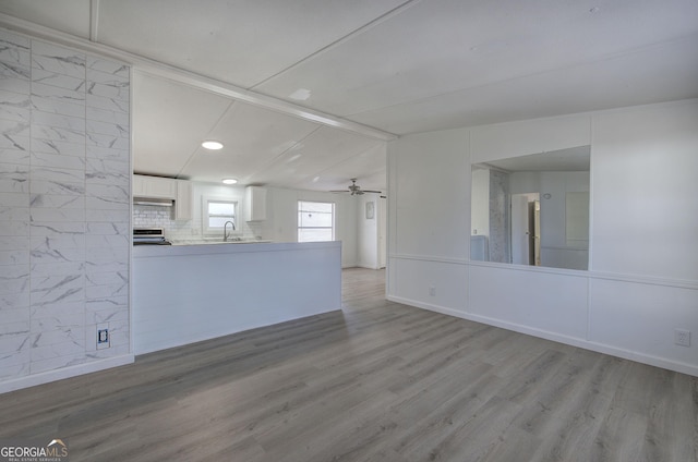 interior space with ceiling fan, sink, light hardwood / wood-style floors, and lofted ceiling