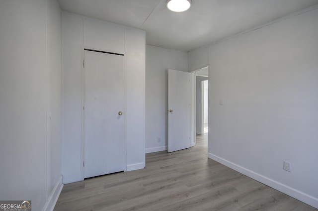 unfurnished bedroom with light hardwood / wood-style flooring and a closet