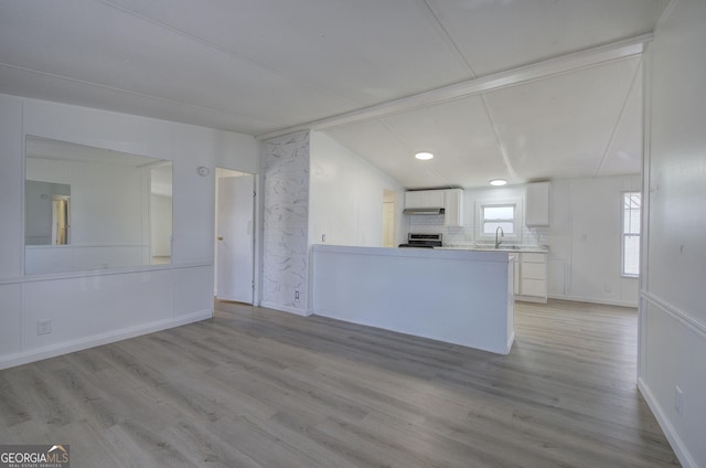 kitchen featuring white cabinetry, sink, kitchen peninsula, stove, and light wood-type flooring