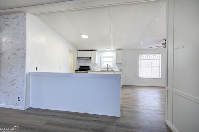 kitchen featuring kitchen peninsula, stainless steel range, sink, vaulted ceiling with beams, and white cabinetry