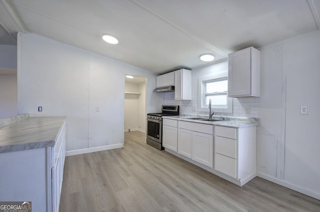 kitchen featuring decorative backsplash, sink, stainless steel gas stove, light hardwood / wood-style floors, and white cabinetry