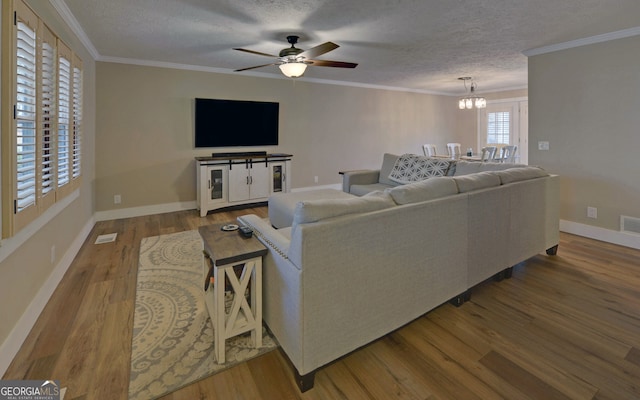 living room with a textured ceiling, crown molding, ceiling fan with notable chandelier, and hardwood / wood-style flooring