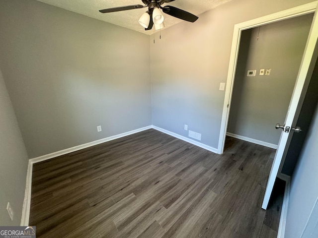 spare room featuring a textured ceiling, ceiling fan, and dark wood-type flooring