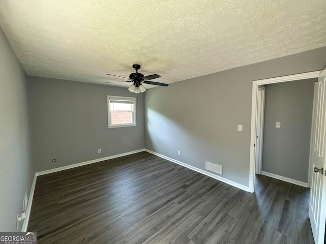 spare room with a textured ceiling, dark hardwood / wood-style floors, and ceiling fan