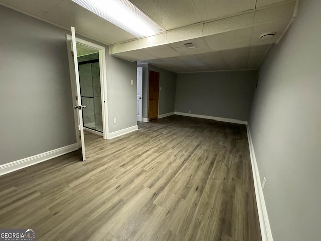 basement featuring a drop ceiling and hardwood / wood-style floors