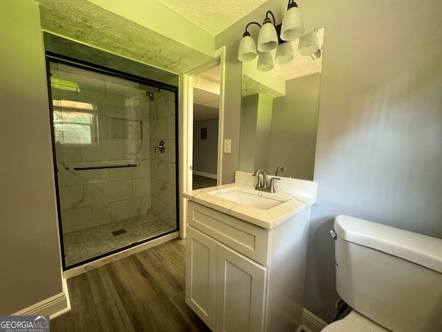 bathroom with vanity, a textured ceiling, a shower with door, wood-type flooring, and toilet