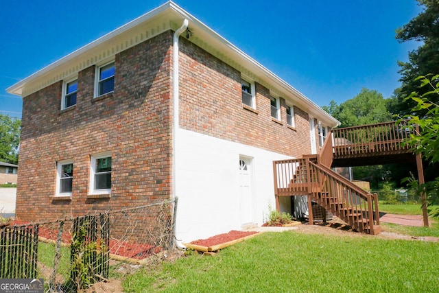 view of side of home with a deck and a lawn