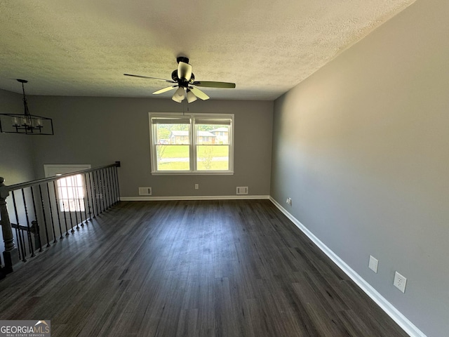 spare room with ceiling fan with notable chandelier, dark hardwood / wood-style flooring, and a textured ceiling