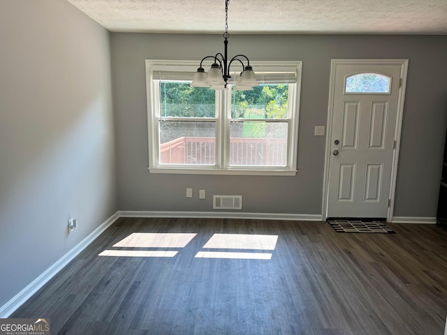 entryway with dark hardwood / wood-style flooring, a textured ceiling, and an inviting chandelier