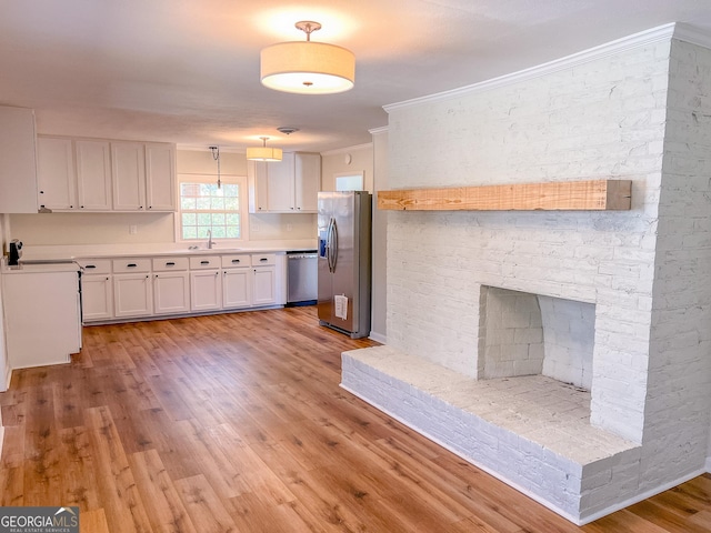 kitchen featuring white cabinetry, stainless steel appliances, ornamental molding, pendant lighting, and sink