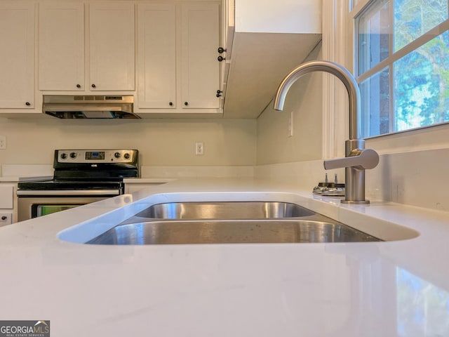 kitchen featuring electric stove, sink, and white cabinetry