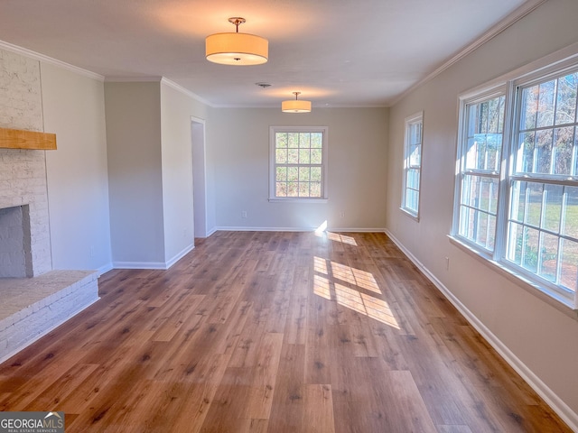 unfurnished living room with a brick fireplace, crown molding, and hardwood / wood-style floors