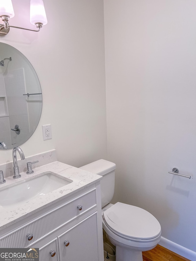 bathroom featuring wood-type flooring, toilet, and vanity