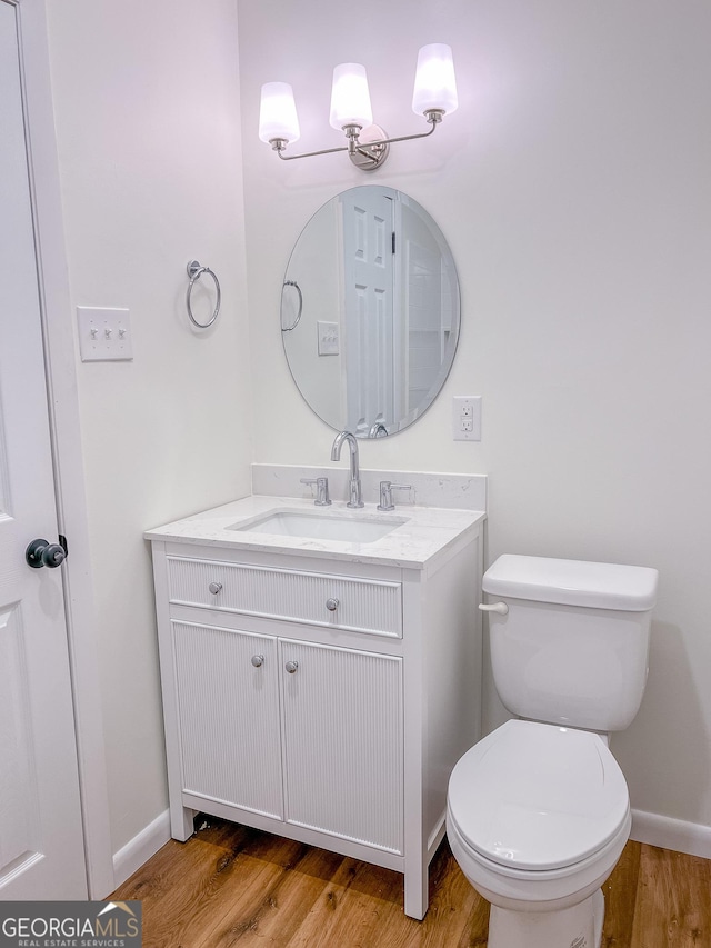 bathroom with toilet, wood-type flooring, and vanity