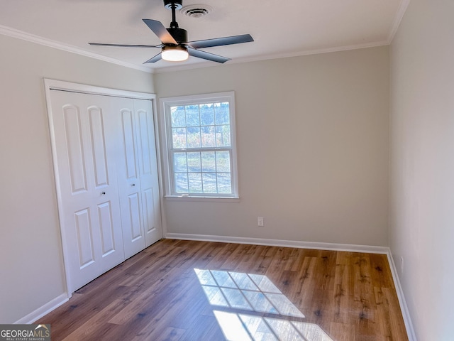 unfurnished bedroom with a closet, crown molding, hardwood / wood-style flooring, and ceiling fan