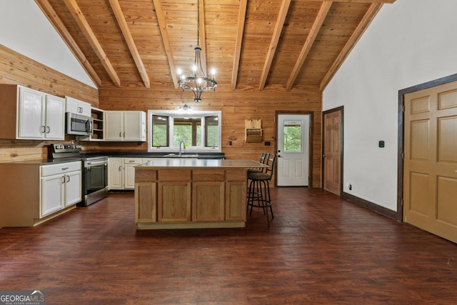 kitchen with decorative light fixtures, a center island, wooden ceiling, appliances with stainless steel finishes, and white cabinets