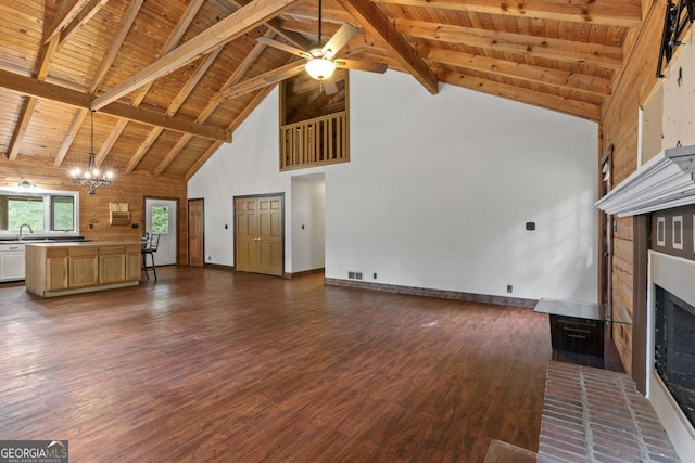 unfurnished living room featuring beam ceiling, wood ceiling, dark hardwood / wood-style floors, a fireplace, and ceiling fan with notable chandelier