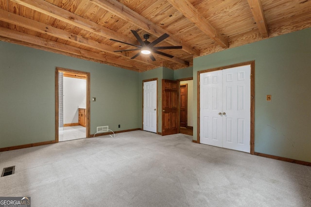 unfurnished bedroom featuring ensuite bath, light carpet, wooden ceiling, beamed ceiling, and ceiling fan