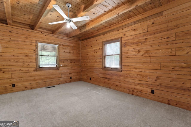 empty room with beamed ceiling, carpet floors, wooden walls, and wood ceiling