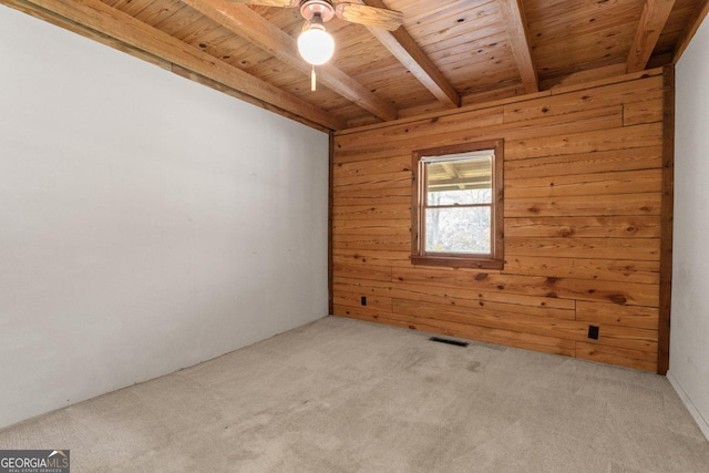 unfurnished room featuring wooden walls, light colored carpet, wooden ceiling, and beam ceiling