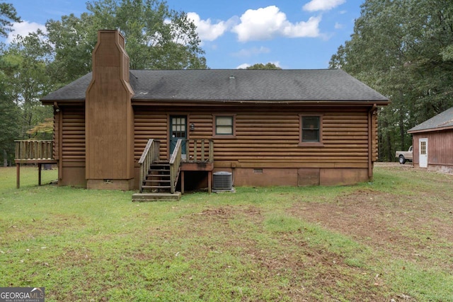 rear view of house featuring central AC and a lawn