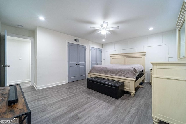 bedroom with ceiling fan, dark hardwood / wood-style floors, and two closets