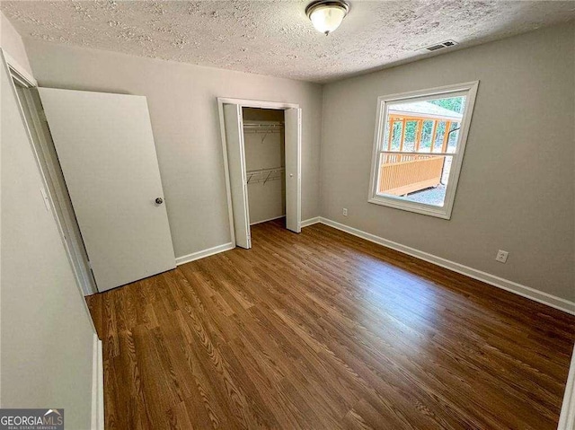 unfurnished bedroom with dark hardwood / wood-style floors, a textured ceiling, and a closet