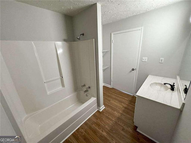 bathroom with vanity, wood-type flooring, a textured ceiling, and bathing tub / shower combination