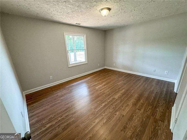 spare room with dark wood-type flooring and a textured ceiling