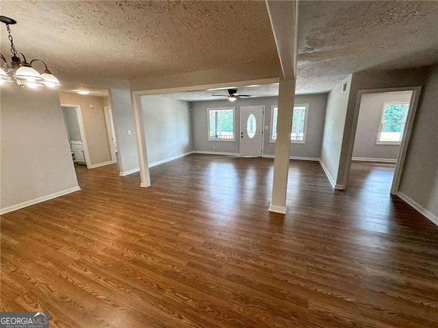 unfurnished living room with a healthy amount of sunlight, a textured ceiling, and dark wood-type flooring