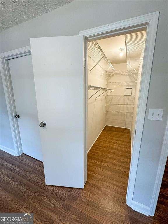 walk in closet with dark hardwood / wood-style floors and vaulted ceiling