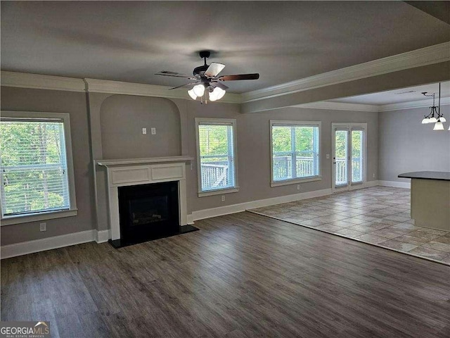 unfurnished living room featuring plenty of natural light, crown molding, and ceiling fan with notable chandelier