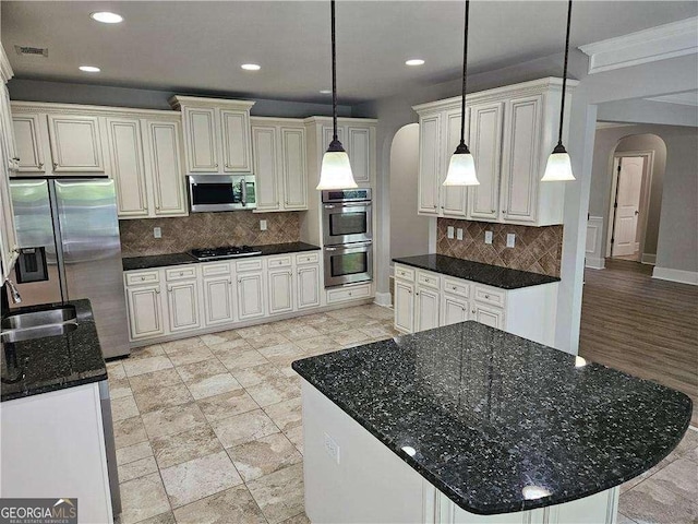 kitchen featuring hanging light fixtures, a kitchen island, stainless steel appliances, and sink