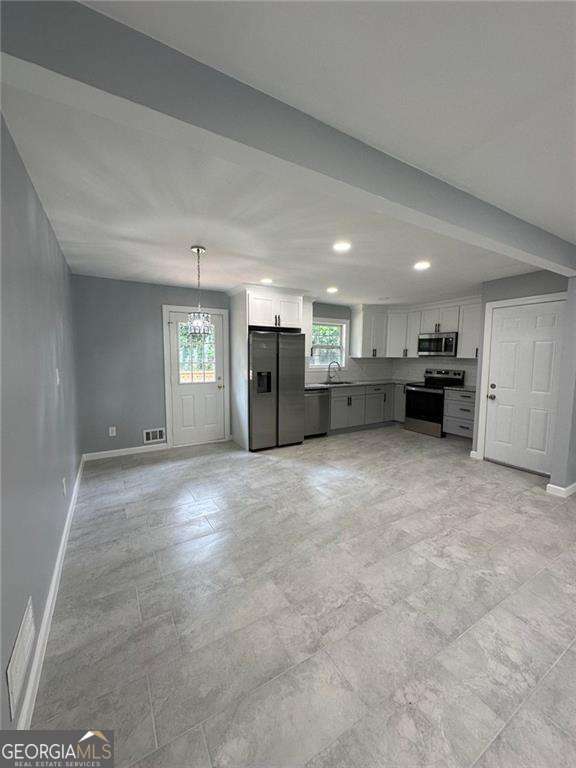 kitchen with a wealth of natural light, sink, white cabinets, and stainless steel appliances