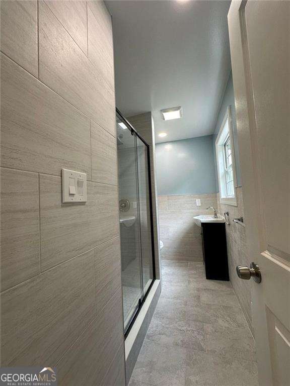 bathroom featuring vanity, tile walls, and a shower with shower door