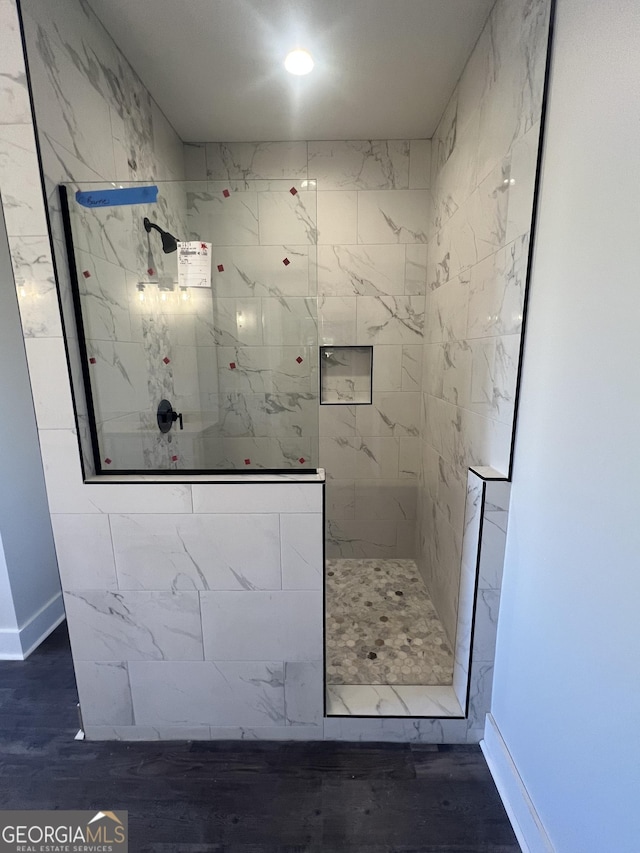 bathroom featuring wood-type flooring and tiled shower