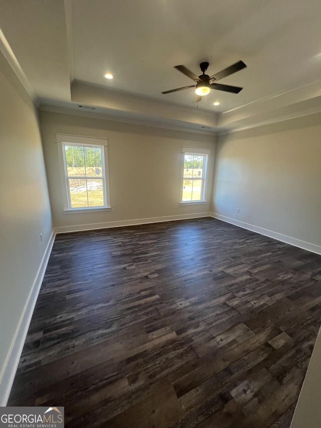 unfurnished room featuring a raised ceiling, ceiling fan, dark hardwood / wood-style flooring, and ornamental molding