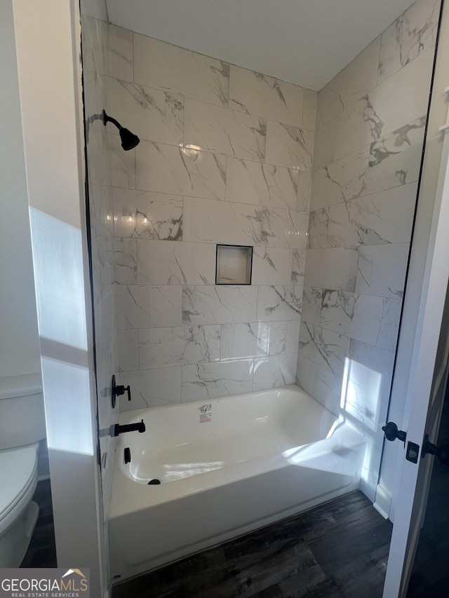 bathroom featuring tiled shower / bath combo and toilet