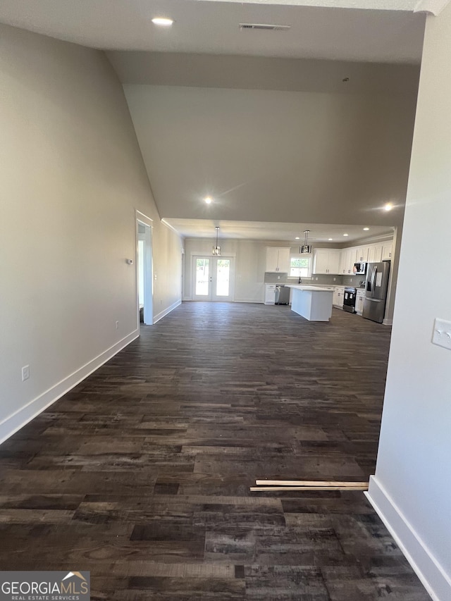 unfurnished living room with french doors, dark wood-type flooring, and vaulted ceiling