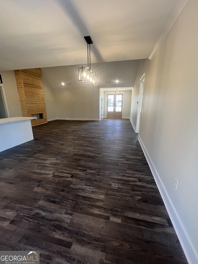 unfurnished dining area featuring dark hardwood / wood-style flooring, crown molding, a fireplace, and an inviting chandelier