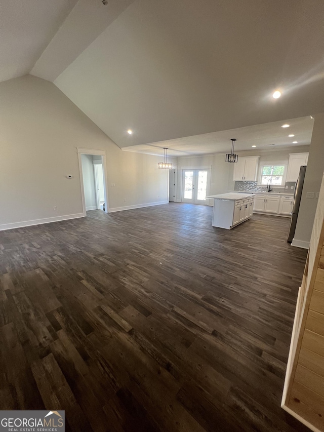 unfurnished living room featuring dark hardwood / wood-style floors, vaulted ceiling, a healthy amount of sunlight, and french doors