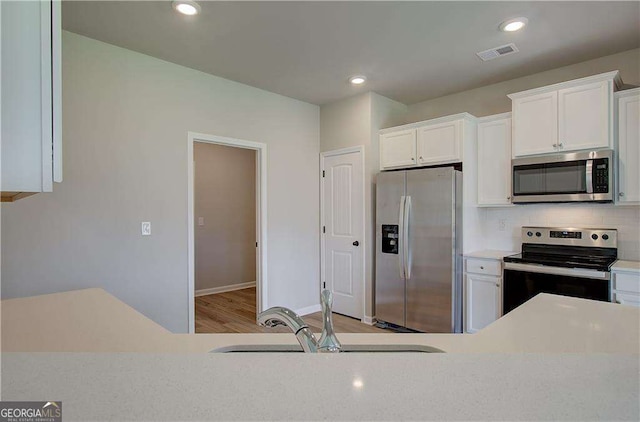 kitchen featuring stainless steel appliances, white cabinetry, tasteful backsplash, and sink