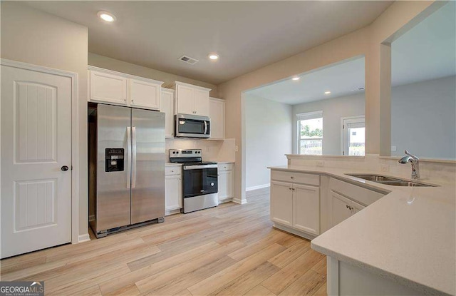 kitchen featuring white cabinetry, sink, stainless steel appliances, and light hardwood / wood-style flooring