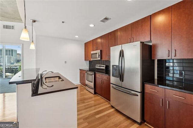 kitchen with sink, stainless steel appliances, light hardwood / wood-style floors, decorative light fixtures, and decorative backsplash