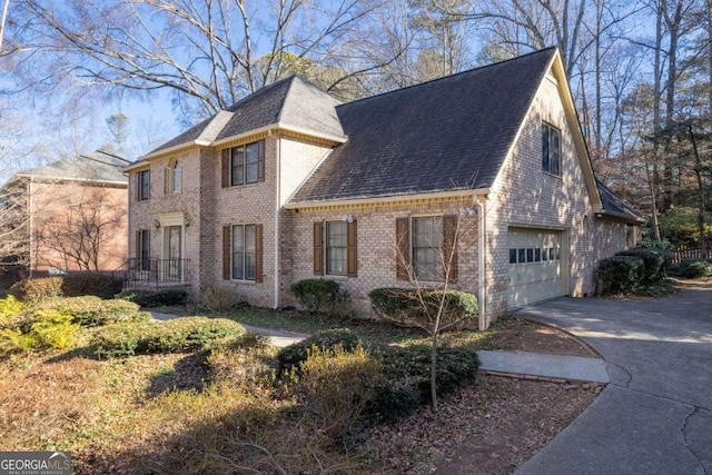 view of property exterior featuring a garage, roof with shingles, concrete driveway, and brick siding