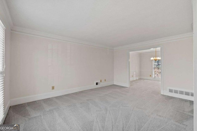 spare room with an inviting chandelier, crown molding, and light colored carpet